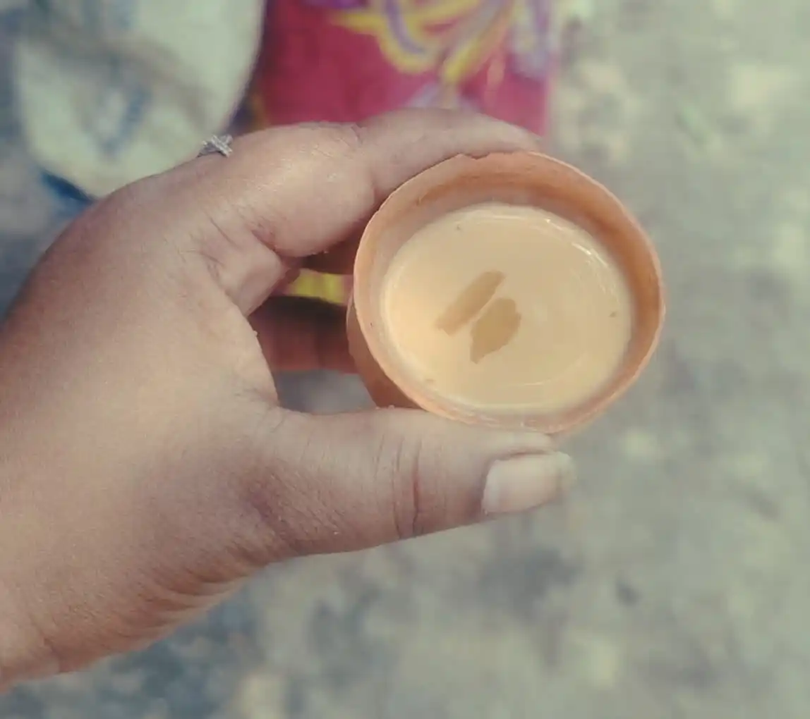 Hand holding a traditional clay cup of tea at a local West Bengal tea stall