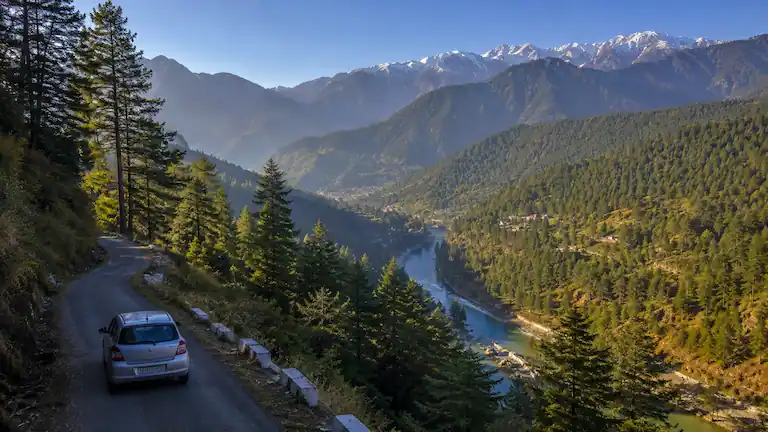 Car driving on mountain road to Barot Valley along Uhl River
