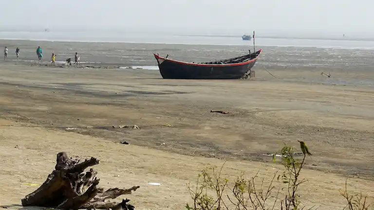 Fishing boat on Bankiput Sea Beach mudflats during low tide.