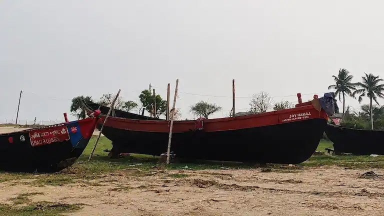 Traditional wooden fishing boats resting on the shore near Lal Kakra Beach.